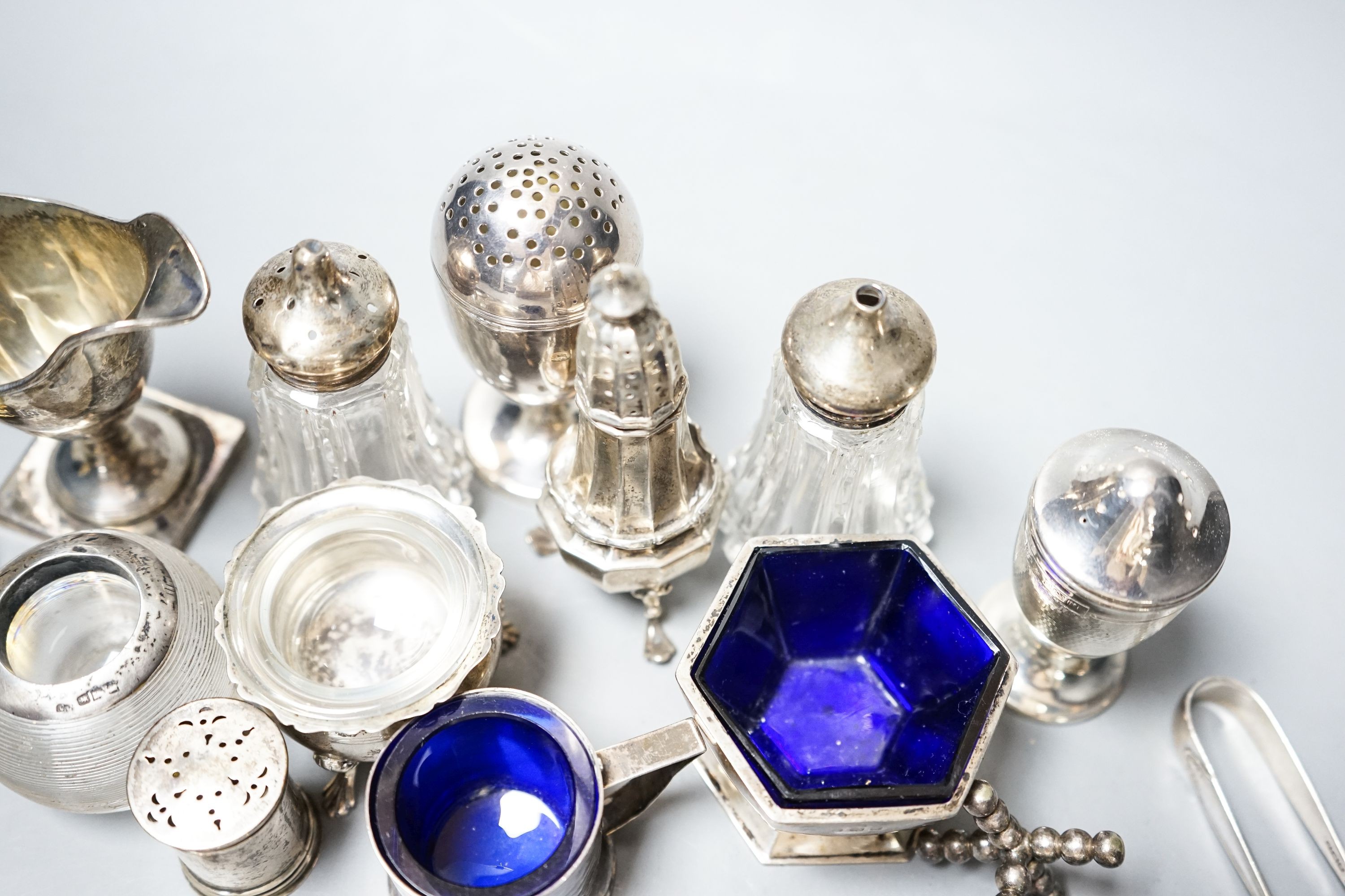 A group of small silver including condiments, match strike, cream jug, plated knife rests etc.
